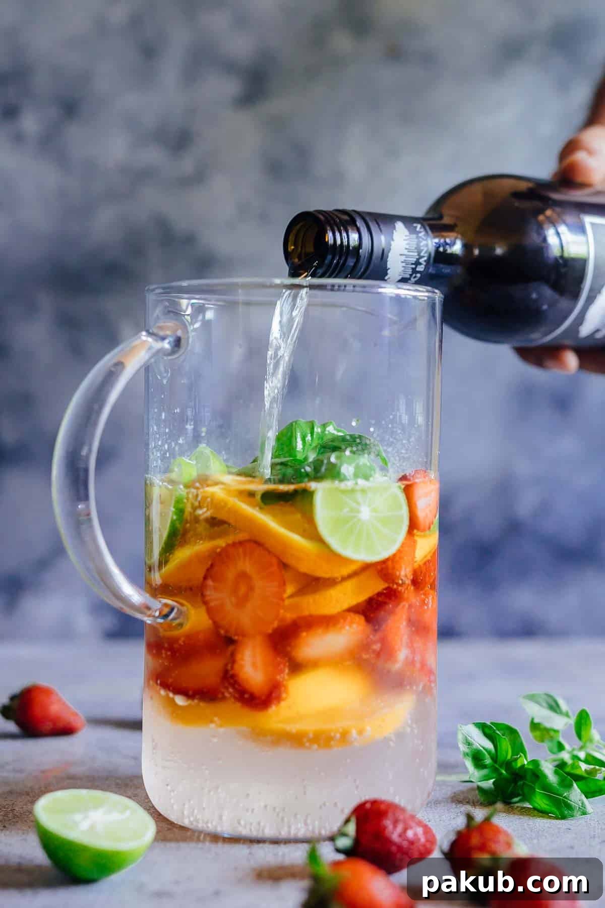 Pouring white wine into a pitcher filled with sliced fruits to make sangria