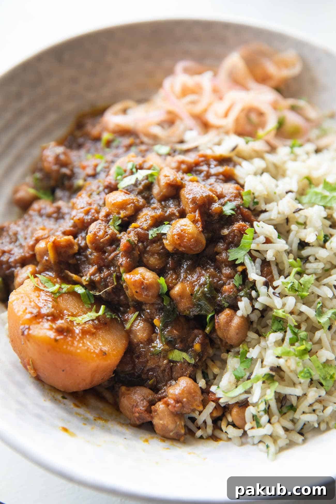 Close up shot of pressure cooker chana masala served in a bowl with rice on the side