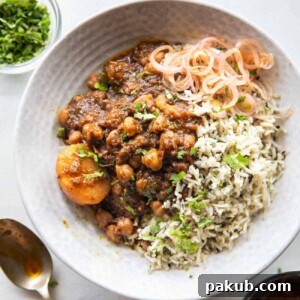 Pressure cooker chana masala served in a bowl with rice and onions on the side