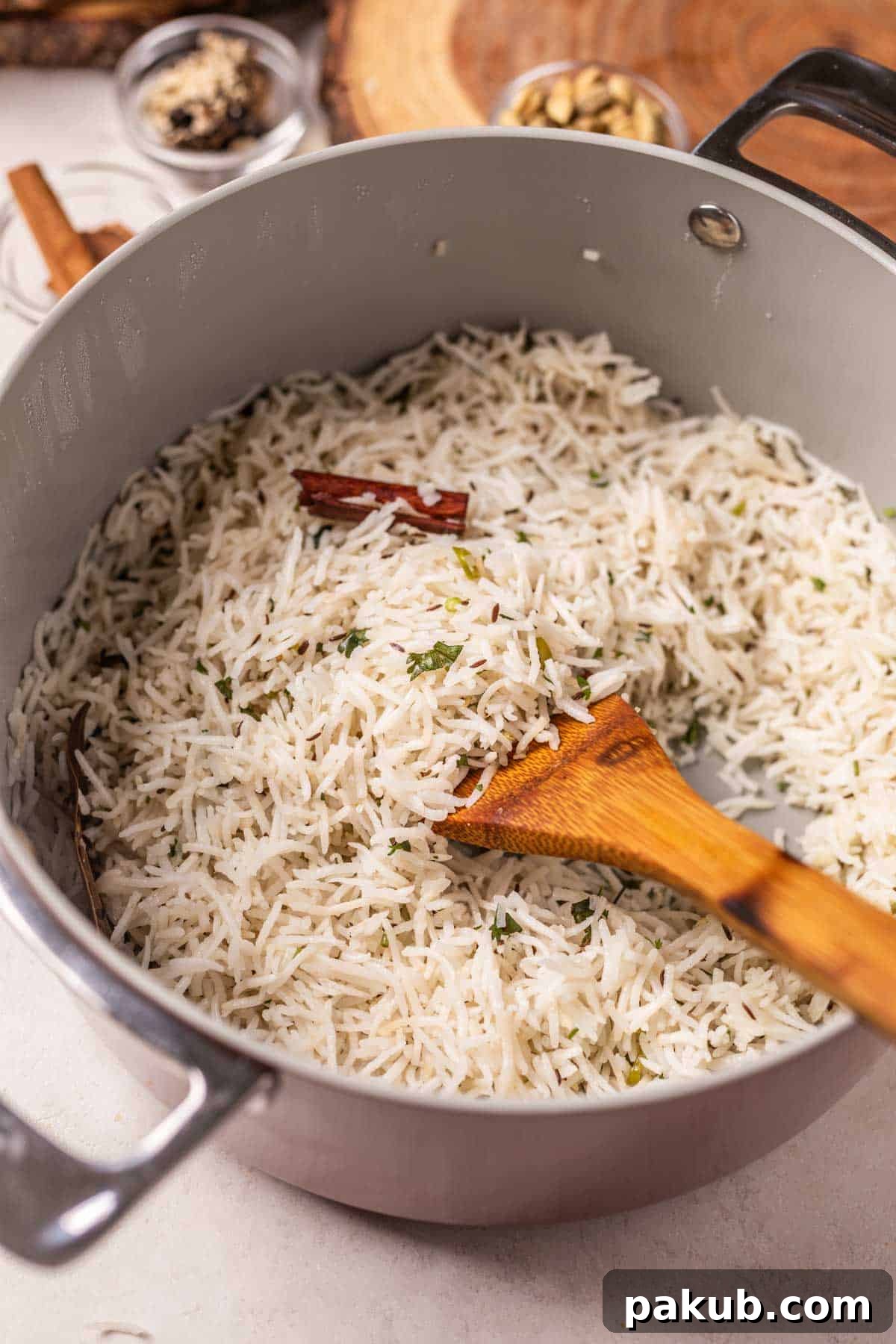 Warm, aromatic Jeera Rice freshly cooked in a pan with a wooden ladle, ready to be served, capturing its fluffy texture and inviting steam.
