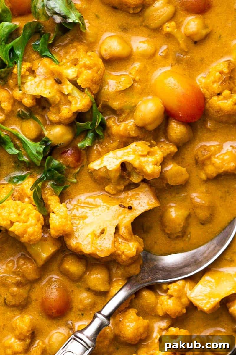 A close-up of the irresistible cauliflower chickpea coconut curry sauce, highlighting its vibrant color and inviting texture. This healthy, plant-based dish is perfect for a quick and flavorful weeknight dinner. #currylovers #plantbased #healthyrecipes #quickdinner #foodie Close-up view of the creamy and richly spiced Cauliflower Chickpea Coconut Curry, showcasing the tender florets and soft chickpeas in the thick, flavorful sauce, ready to be scooped.