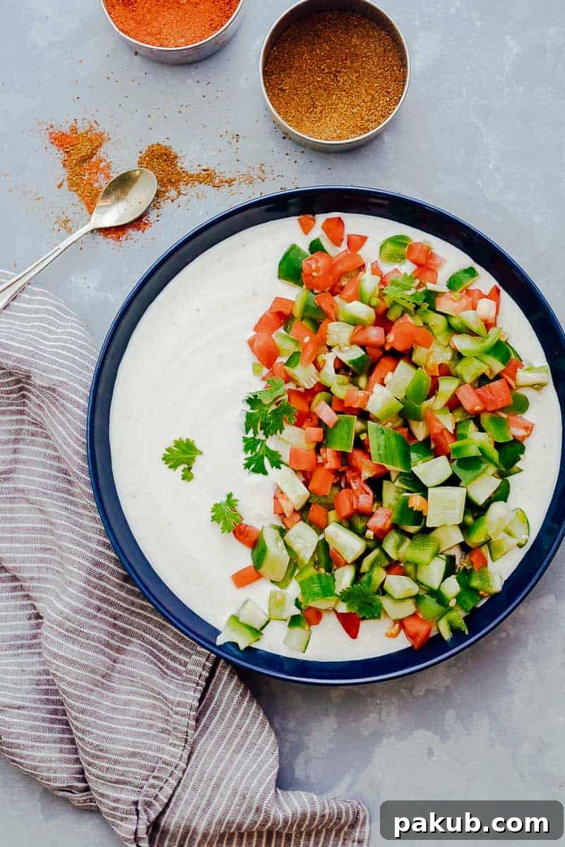 Refreshingly Versatile: The Best Indian Raita Recipes 7 Chopped tomato, cucumber, onions and cilantro being mixed into a bowlful of whisked yogurt