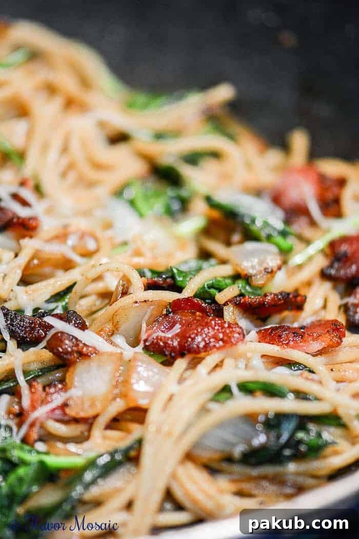 15 Bacon Creations to Make Every Meal a Party 12 A mouth-watering close-up of Bacon Spaghetti Florentine pasta, featuring rich sauce, vibrant spinach, and crispy bacon pieces intertwined with spaghetti.