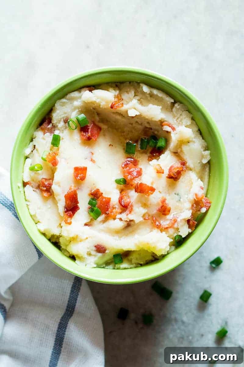 15 Bacon Creations to Make Every Meal a Party 14 A vibrant green bowl brimming with creamy Slow Cooker Mashed Potatoes, generously topped with an abundance of crispy bacon bits, promising ultimate comfort and flavor.