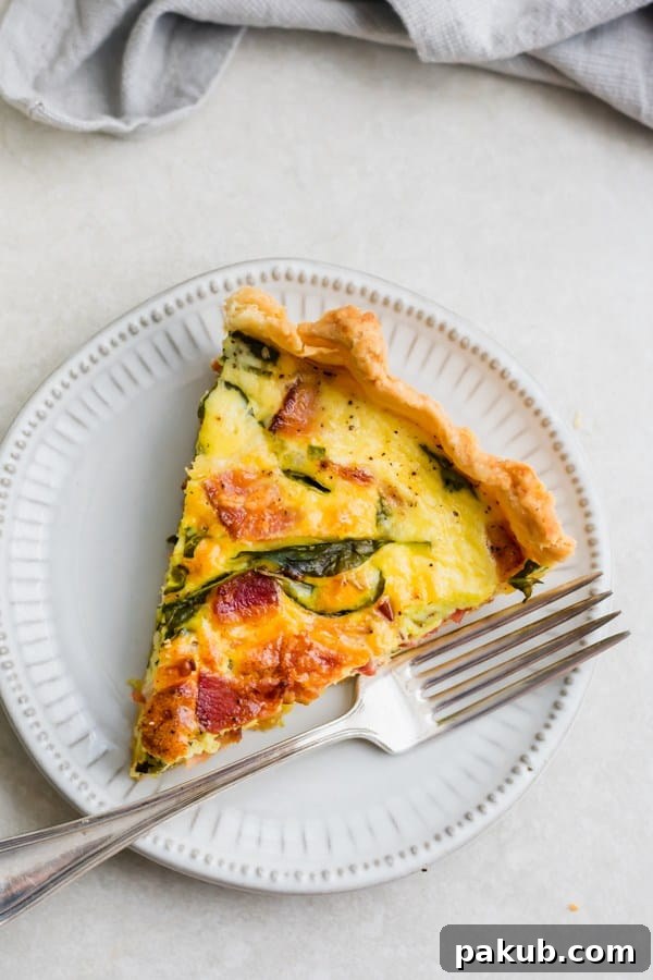 15 Bacon Creations to Make Every Meal a Party 7 A delectable slice of Breakfast Quiche adorned with visible pieces of bacon, resting on a pristine white plate, promising a delightful start to the day.