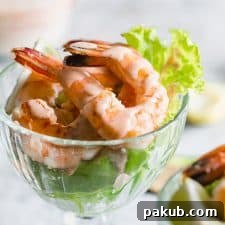 Retro prawn cocktail served in stem glasses with marie rose sauce drizzled over them.