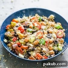 Mediterranean quinoa salad served in a blue bowl sprinkled with crumbled feta.