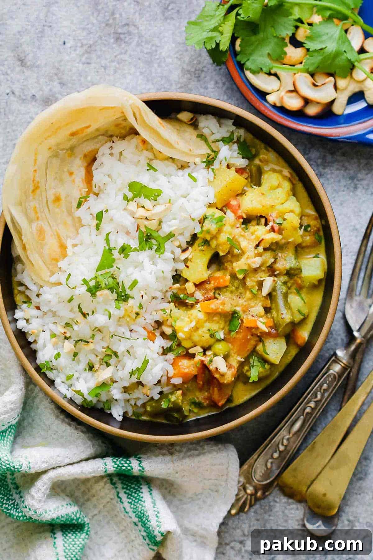 Creamy Vegetable Korma Perfection 3 A bowl of creamy Vegetable Korma Curry, garnished with crunchy cashews and fresh coriander, served with rice and Malabar paratha
