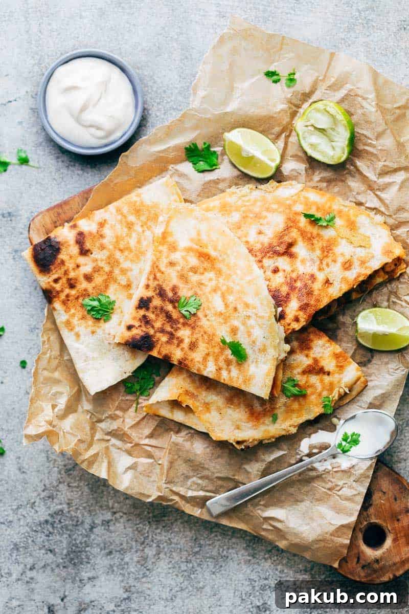 Effortless Chicken Fajita Quesadillas 2 Delicious Chicken Fajita Quesadillas served on a rustic wooden board, garnished with fresh cilantro, lime wedges, and a side of creamy sour cream