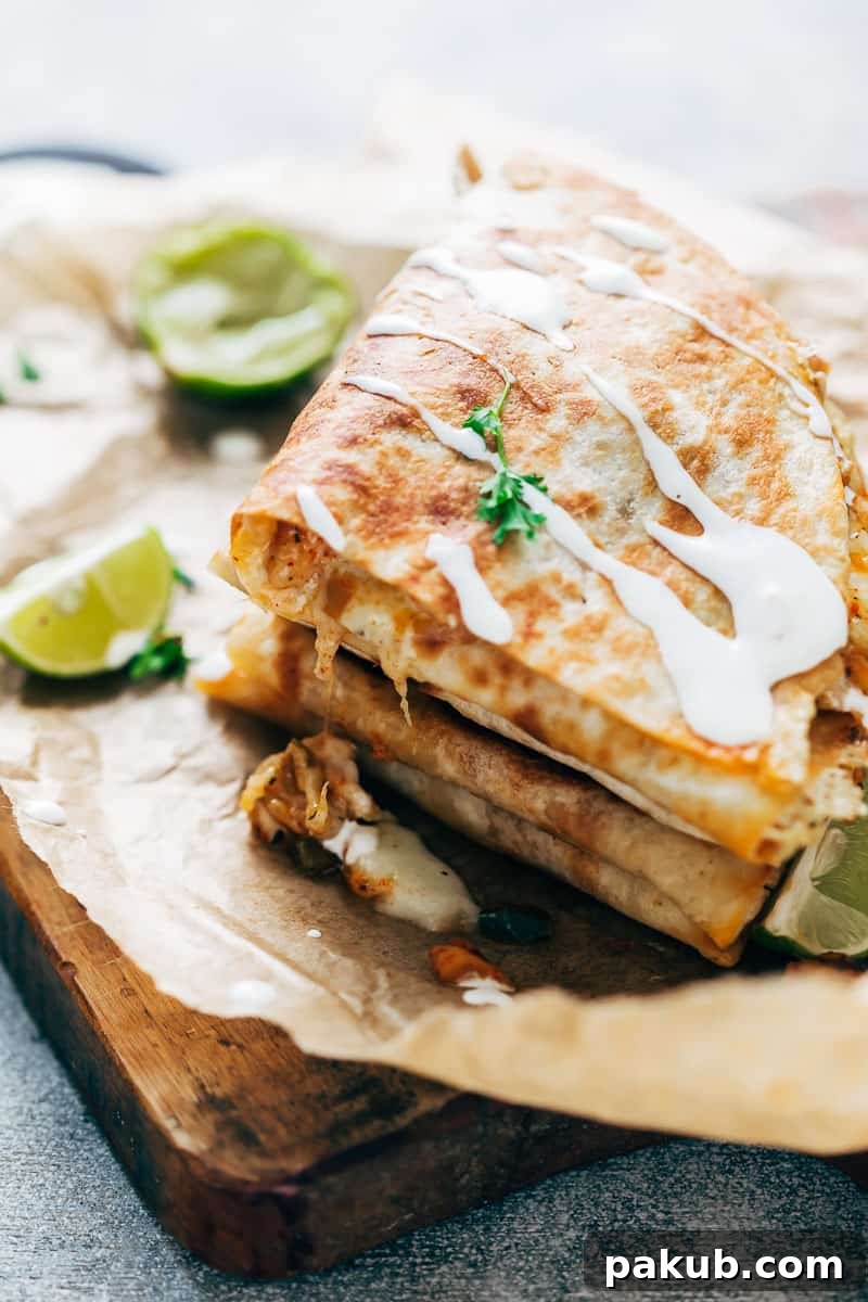 Effortless Chicken Fajita Quesadillas 3 Close-up view of golden-brown chicken fajita quesadillas, showing the crispy tortilla edges and melted cheese, with a delicate drizzle of sour cream on top