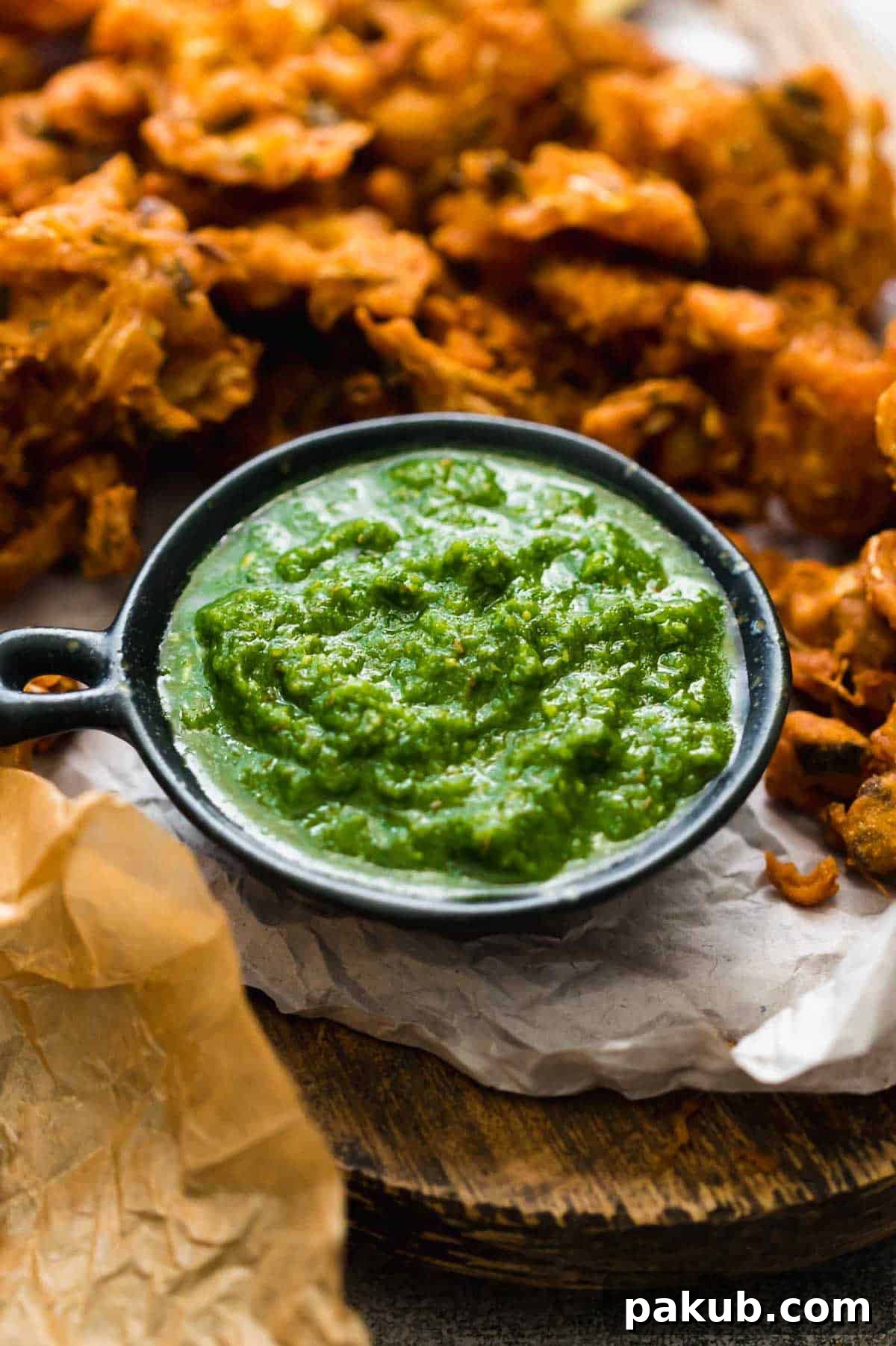 Green Coriander Chutney The Perfect Dip for Anything 3 Close-up of freshly made Green Cilantro Chutney, garnished with a few sprigs of cilantro, served with crispy Indian fritters on the side.
