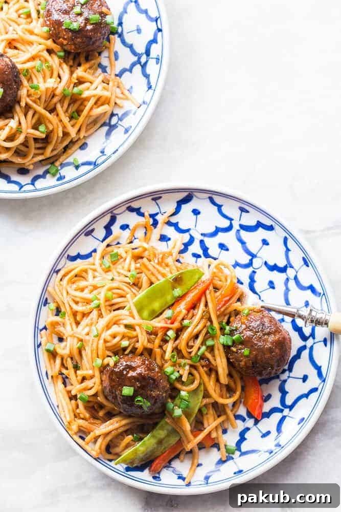 top shot of veg noodles and manchurian served on a white and blue plate