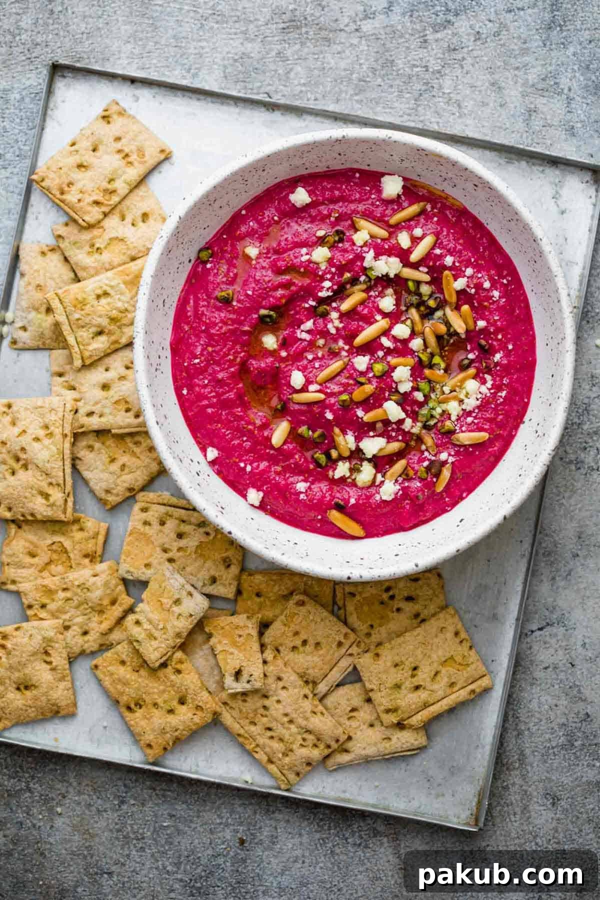 Egyptian Beetroot Dip served on a tray with crackers, garnished with feta and nuts.