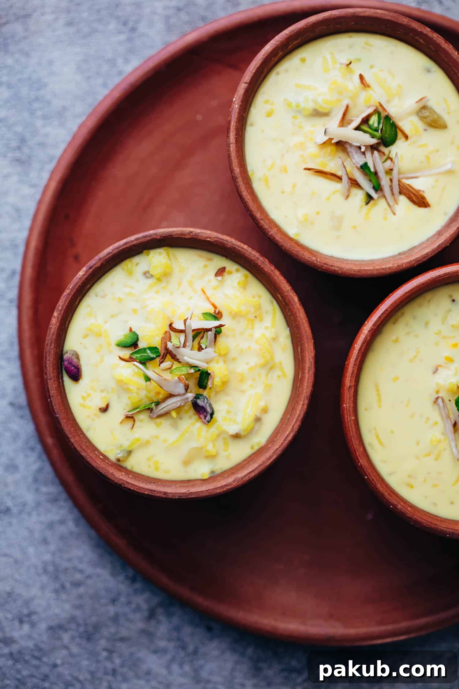 Effortless Indian Rice Kheer 2 Overhead shot of traditional Indian Rice Kheer served in rustic mud pots, garnished with chopped nuts and saffron strands.