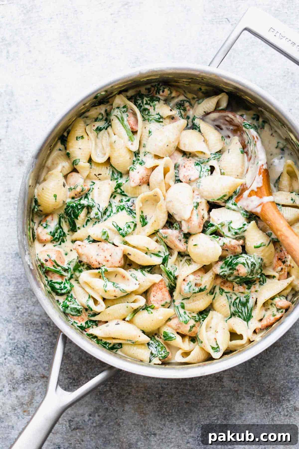 Creamy chicken florentine pasta served in a pan, garnished with fresh herbs and a hint of cheese.