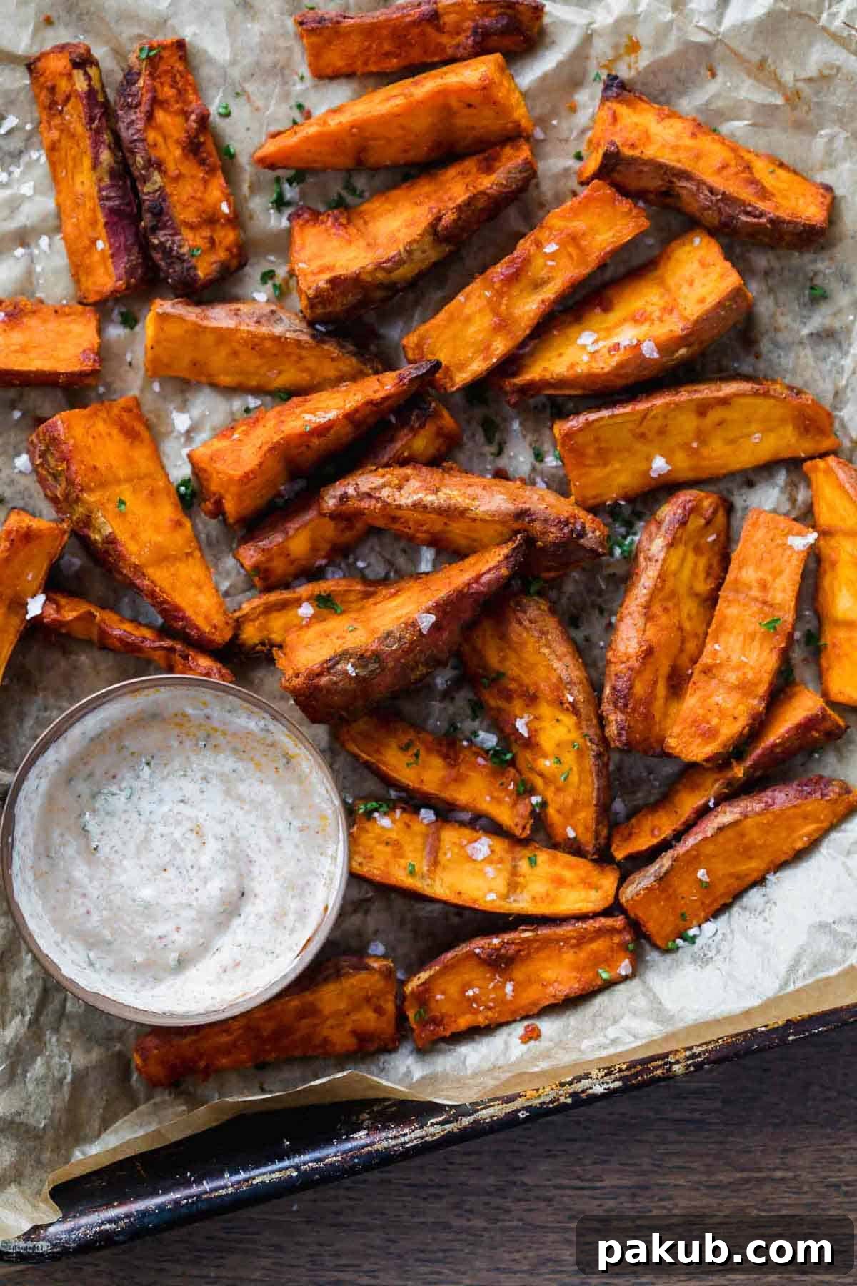 Fiery Zest Sweet Potato Wedges 2 Chilli Lime Sweet Potato Wedges baked and served on a tray with a dipping sauce. Golden brown with flecks of seasoning.