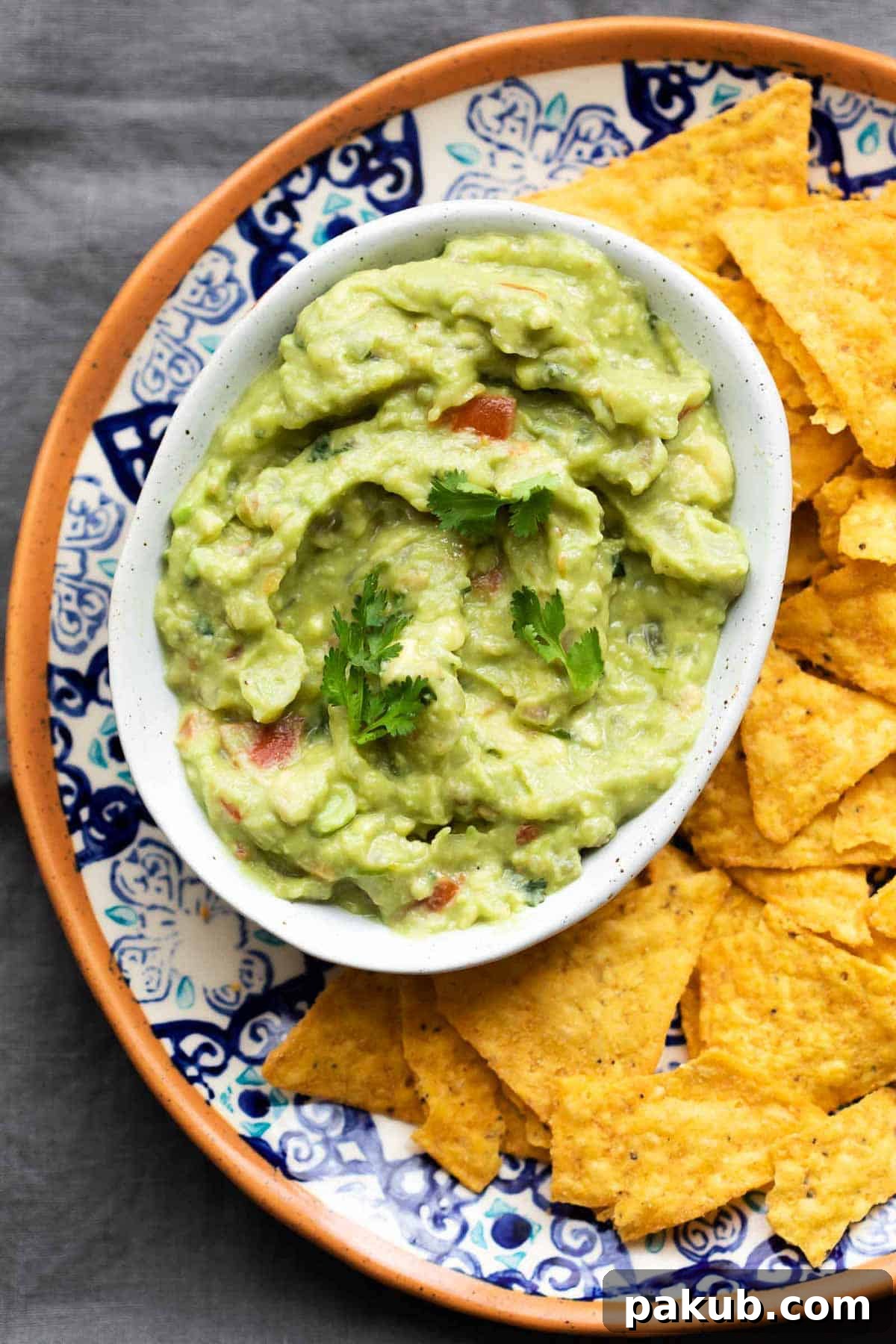 Insanely Delicious Homemade Guacamole 4 Two bowls of homemade guacamole with different textures - one smooth and one chunky - served with a variety of tortilla chips.