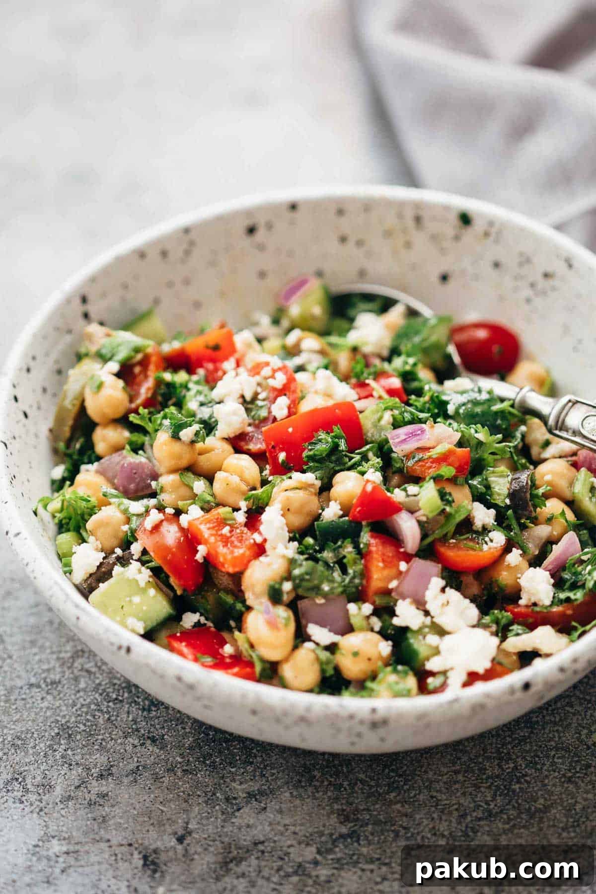 Easy Mediterranean chickpea salad served in a ceramic bowl with a spoon, ready to be enjoyed.