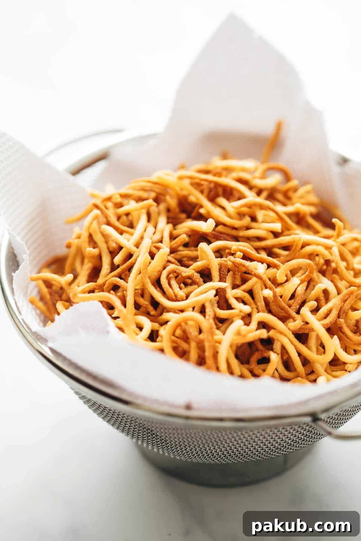 Freshly made Crispy Fried Noodles, golden brown and perfectly crunchy, stored on tissue paper in a sieve to drain excess oil