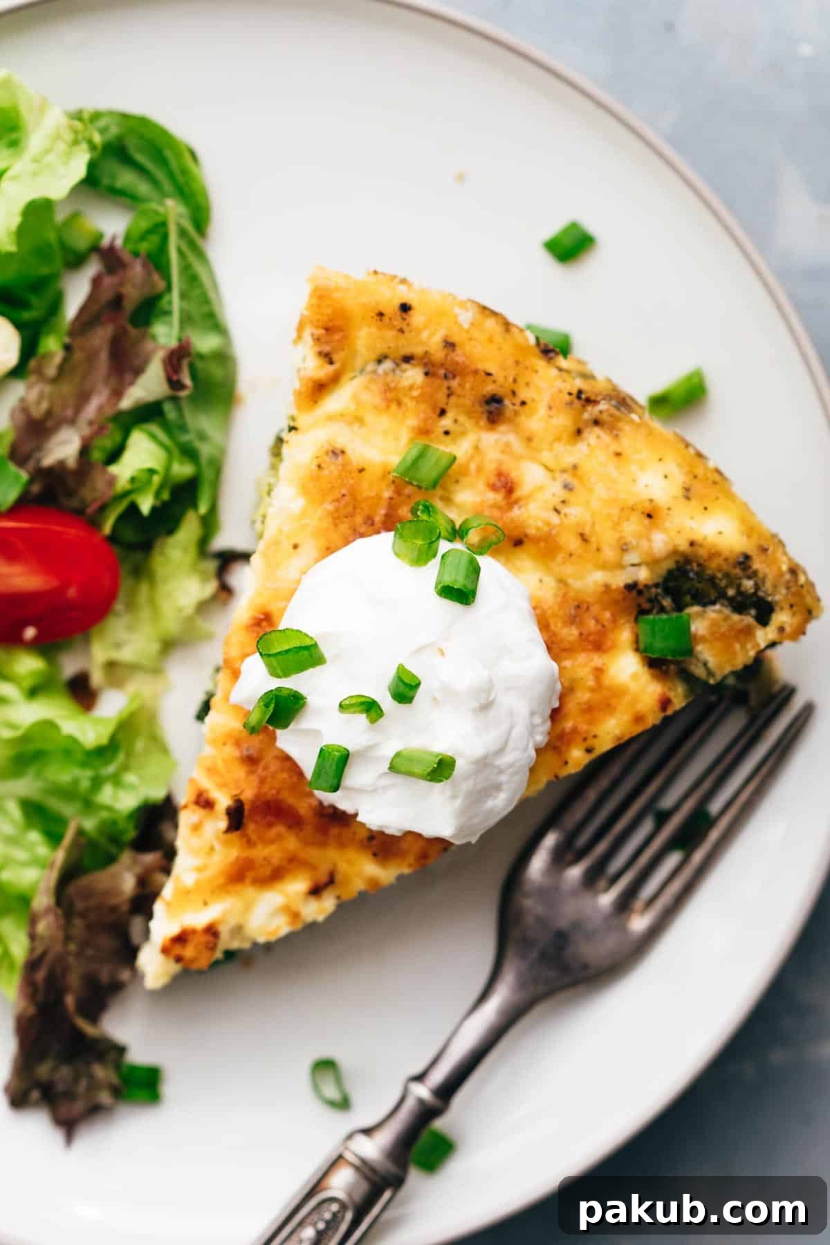 Rustic Cast Iron Spinach Potato Frittata 2 A vibrant slice of Spinach Potato Veggie Frittata, beautifully golden, topped with a dollop of cool sour cream and a sprinkle of fresh green onions, ready to be enjoyed.