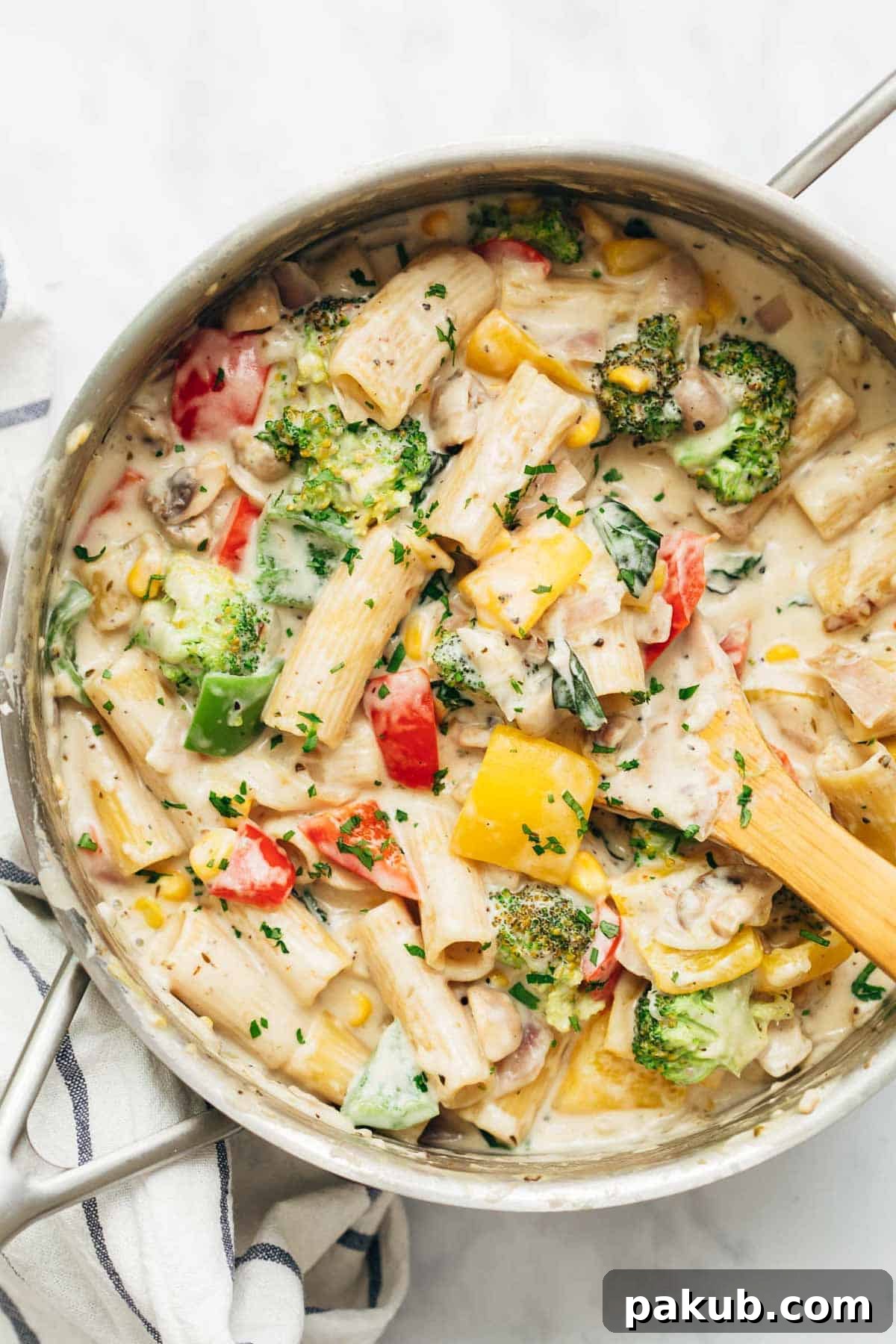 Creamy Garden Vegetable Pasta 2 White sauce pasta with colorful vegetables served directly from the stovetop in a pan, garnished with fresh herbs.