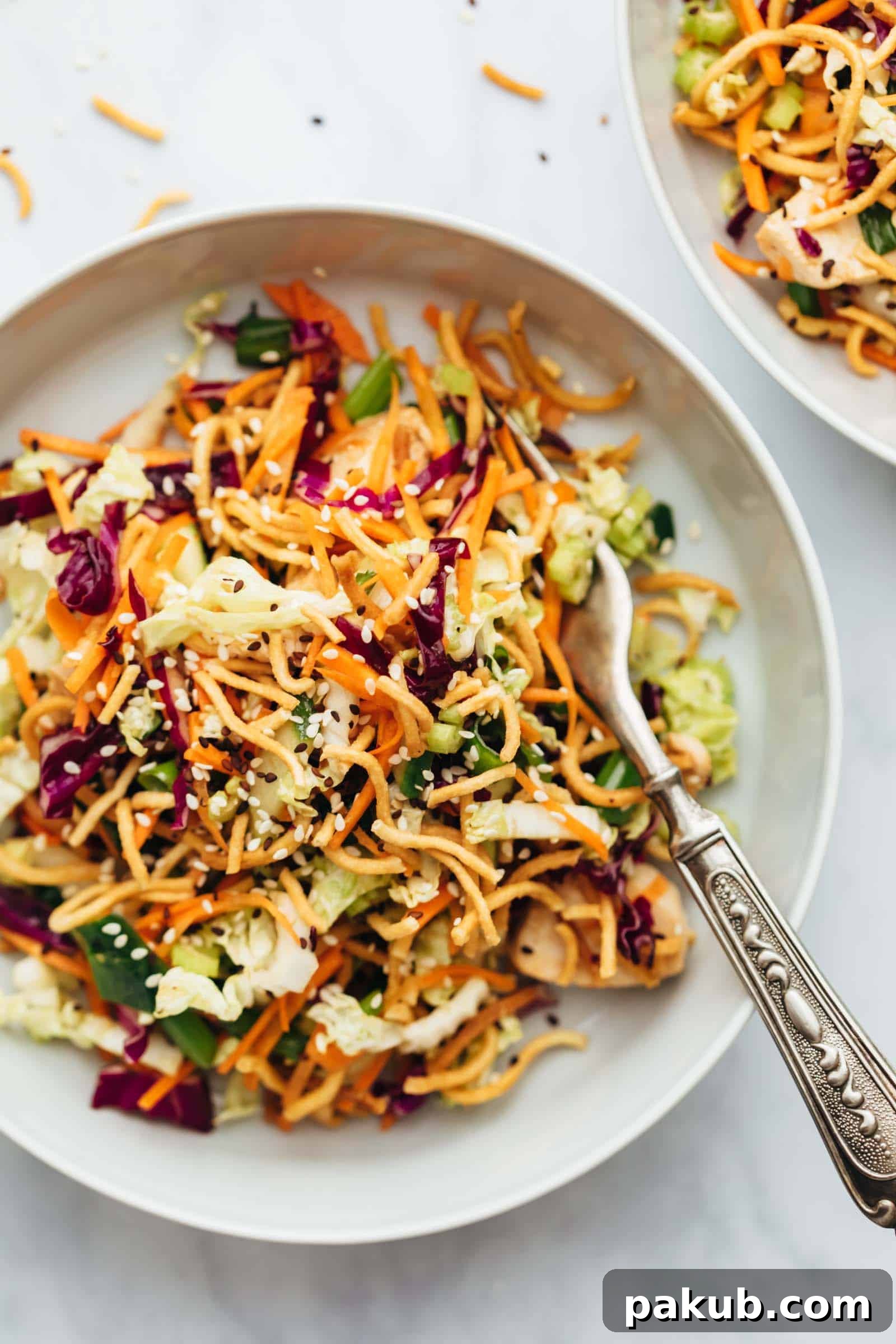 Mandarin Ginger Chicken Crunch Salad 2 Crunchy Chinese chicken salad served in a bowl with a fork, showcasing vibrant vegetables and crispy noodles