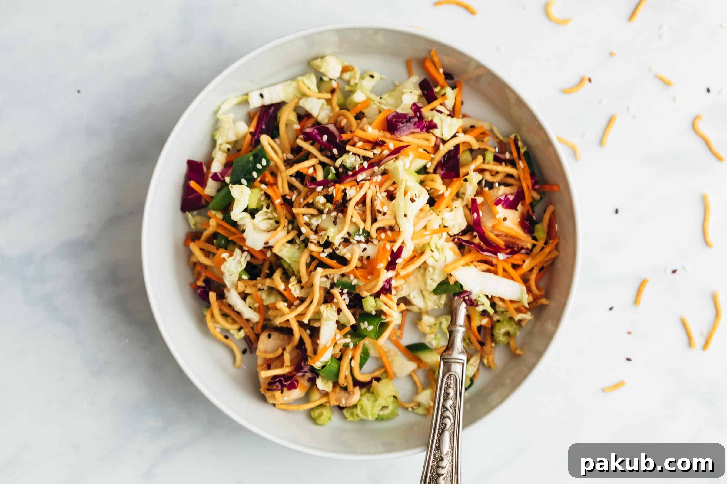 Mandarin Ginger Chicken Crunch Salad 3 Close-up of vibrant Chinese chicken salad in a bowl, showing shredded chicken, colorful vegetables, and crispy noodles.