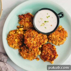 Mexican corn fritters served on a blue plate with a creamy dip on the side
