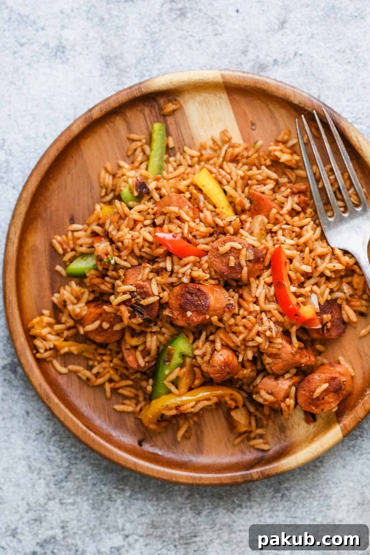 One Pot Mexican Rice and Sausages served on a white plate with a spoonful of sour cream