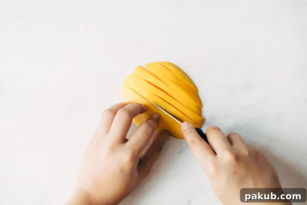 Easy Step-by-Step Guide to Cutting a Mango 12 A neatly peeled mango being sliced into uniformly thin wedges, demonstrating precision for various culinary uses.
