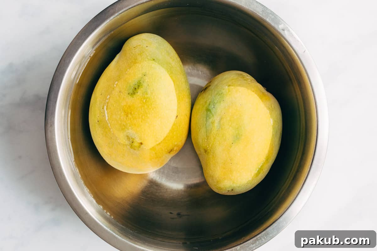 Easy Step-by-Step Guide to Cutting a Mango 3 A fresh, ripe mango being thoroughly soaked in a bowl of clean water before the cutting process, a traditional method to enhance flavor and reduce sap.