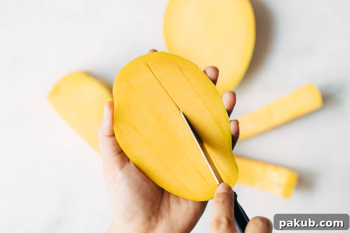 Easy Step-by-Step Guide to Cutting a Mango 7 Precise vertical cuts being made into the flesh of a mango cheek, preparing it for dicing or creating uniform wedges.