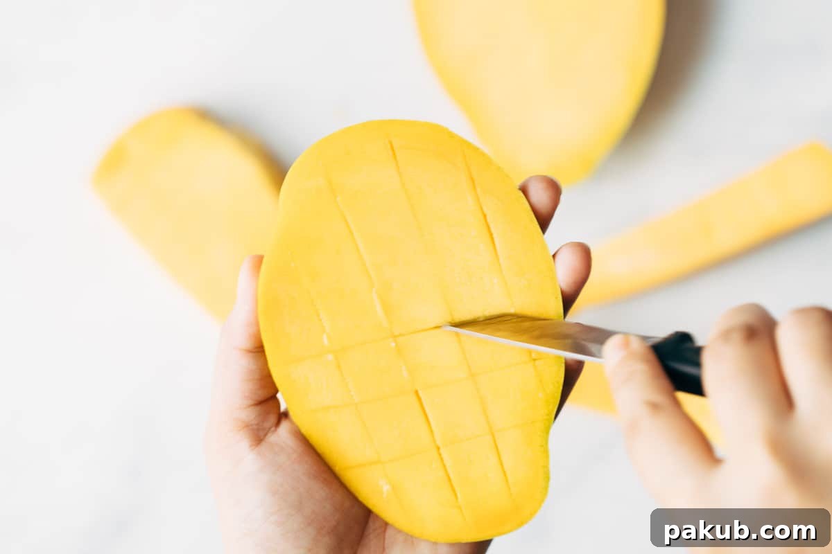 Easy Step-by-Step Guide to Cutting a Mango 8 Horizontal cuts completing the grid pattern on a mango cheek, creating perfectly defined dices within the skin, ready to be scooped.