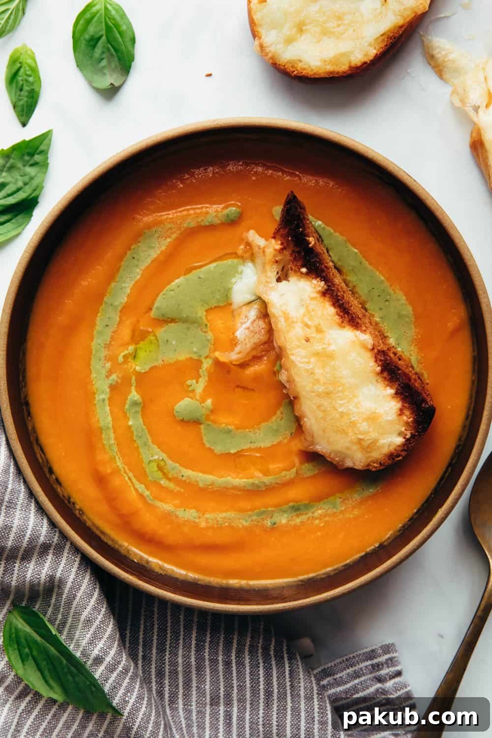 Roasted tomato pesto soup served in a bowl with toasted cheesy bread