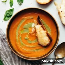 Roasted tomato pesto soup served in a bowl with toasted cheesy bread
