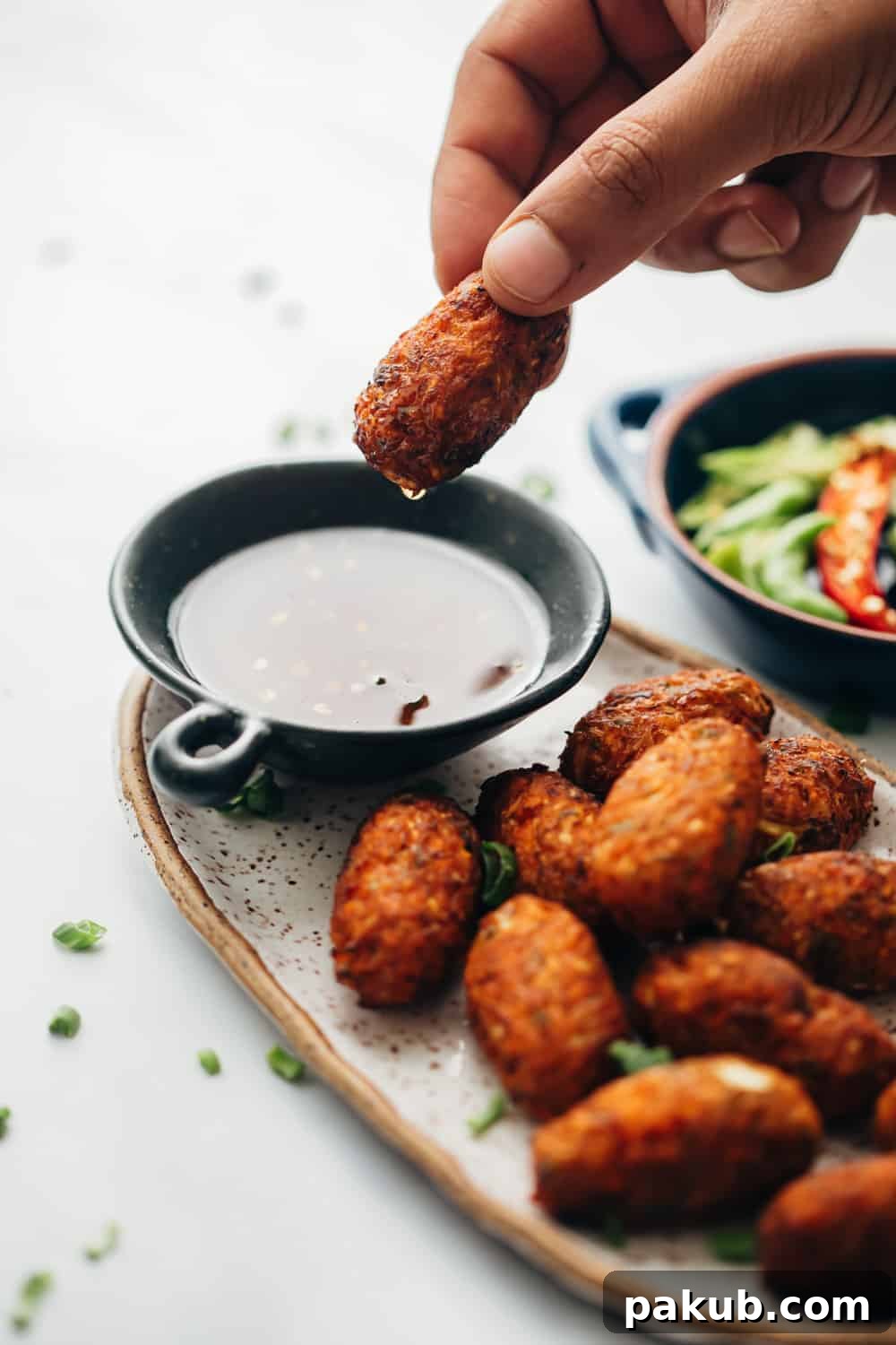 Sichuan Zing with Crispy Veggie Bites 2 Crispy veg nuggets being dipped in vibrant Sichuan sauce, showcasing their golden-brown exterior.