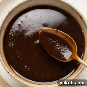 A spoonful of tamarind chutney being taken out of a bowl