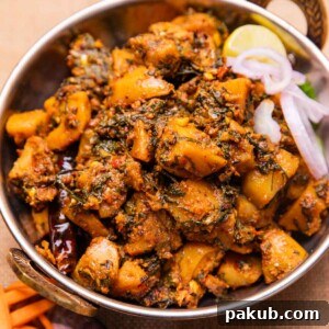 dhaba style aloo palak served in a bowl with sliced onions and a lemon wedge