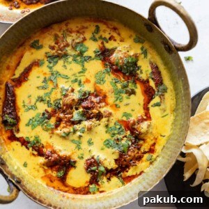 vibrant kadhi pakora garnished with a tadka and coriander leaves, served in a copper handi