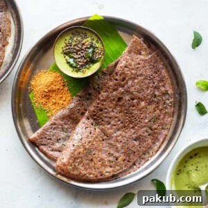 Ragi dosa served in a steel plate on a banana leaf with coconut chutney and podi