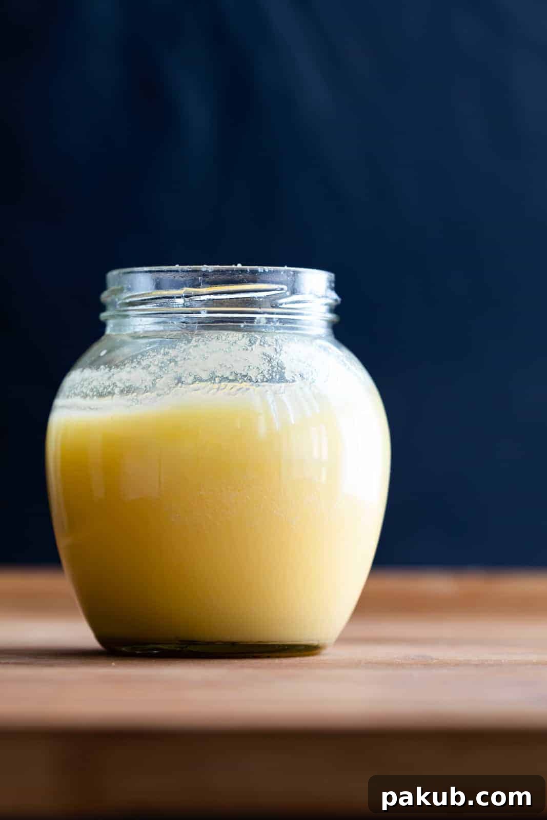 Jar of golden homemade ghee glistening in a kitchen setting.