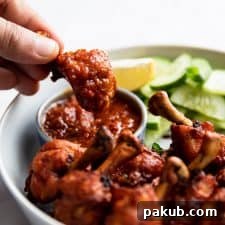 Dipping chicken lollipop in schezwan sauce