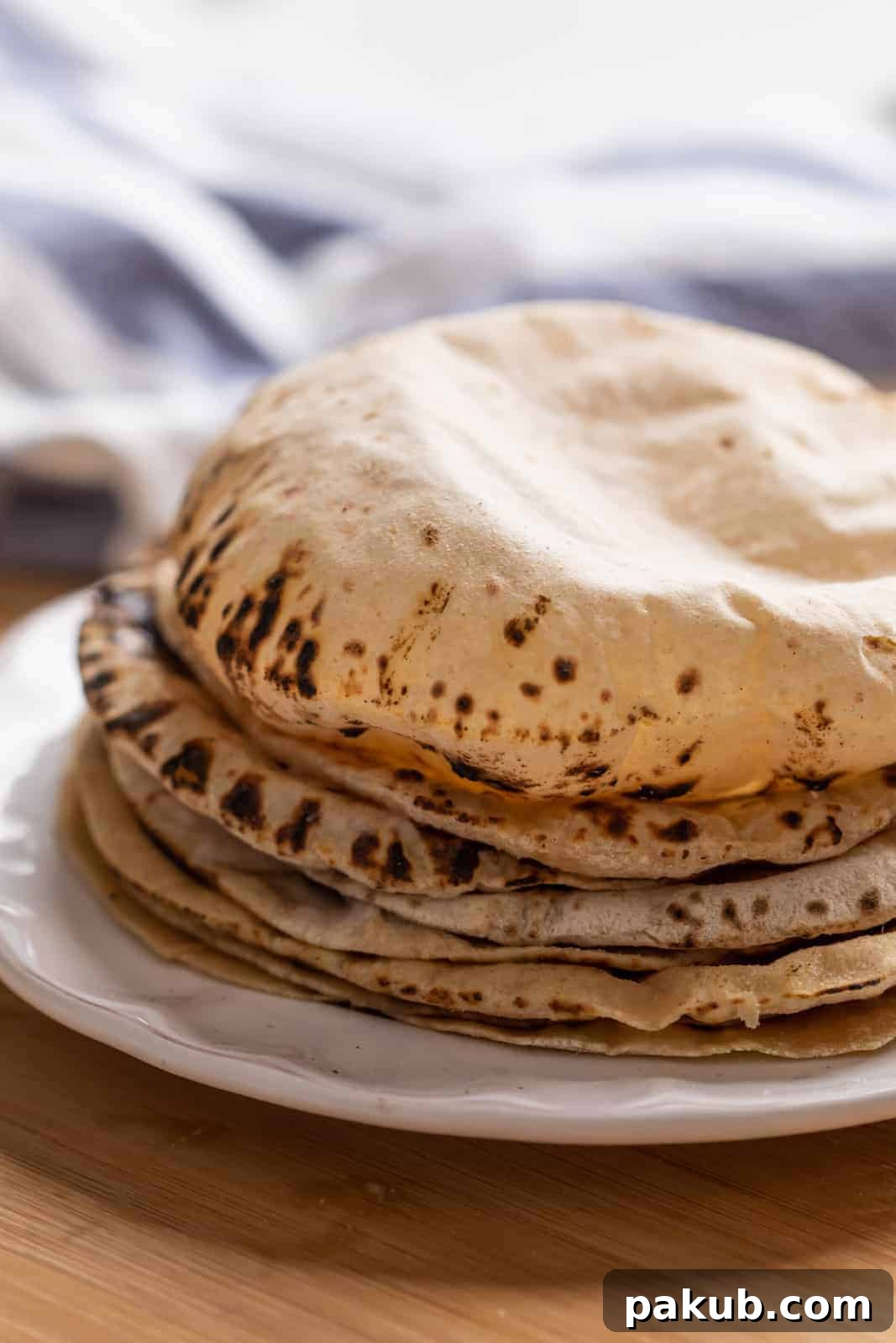Mastering Soft Rotis at Home 2 Soft, puffy rotis stacked neatly on a plate, ready to be served, gleaming with melted ghee.
