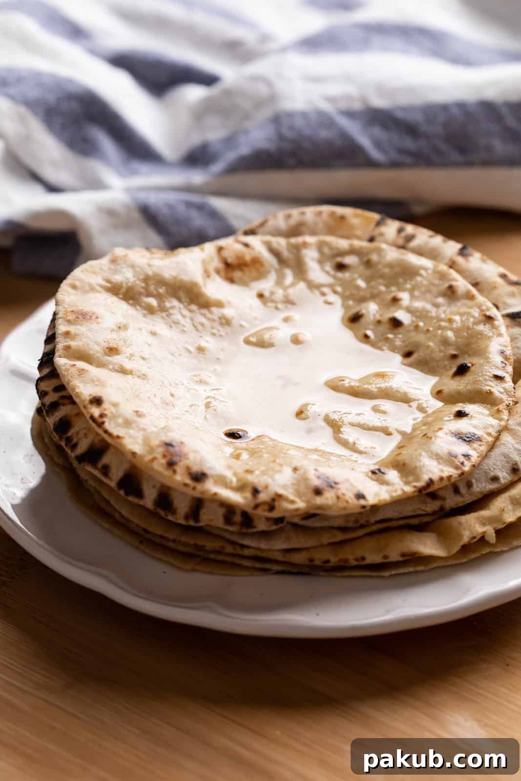 Mastering Soft Rotis at Home 4 Soft, freshly cooked rotis smeared generously with golden ghee, glistening and ready for a meal.