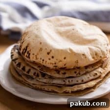 Soft puffy rotis stacked on a plate, ready to eat.