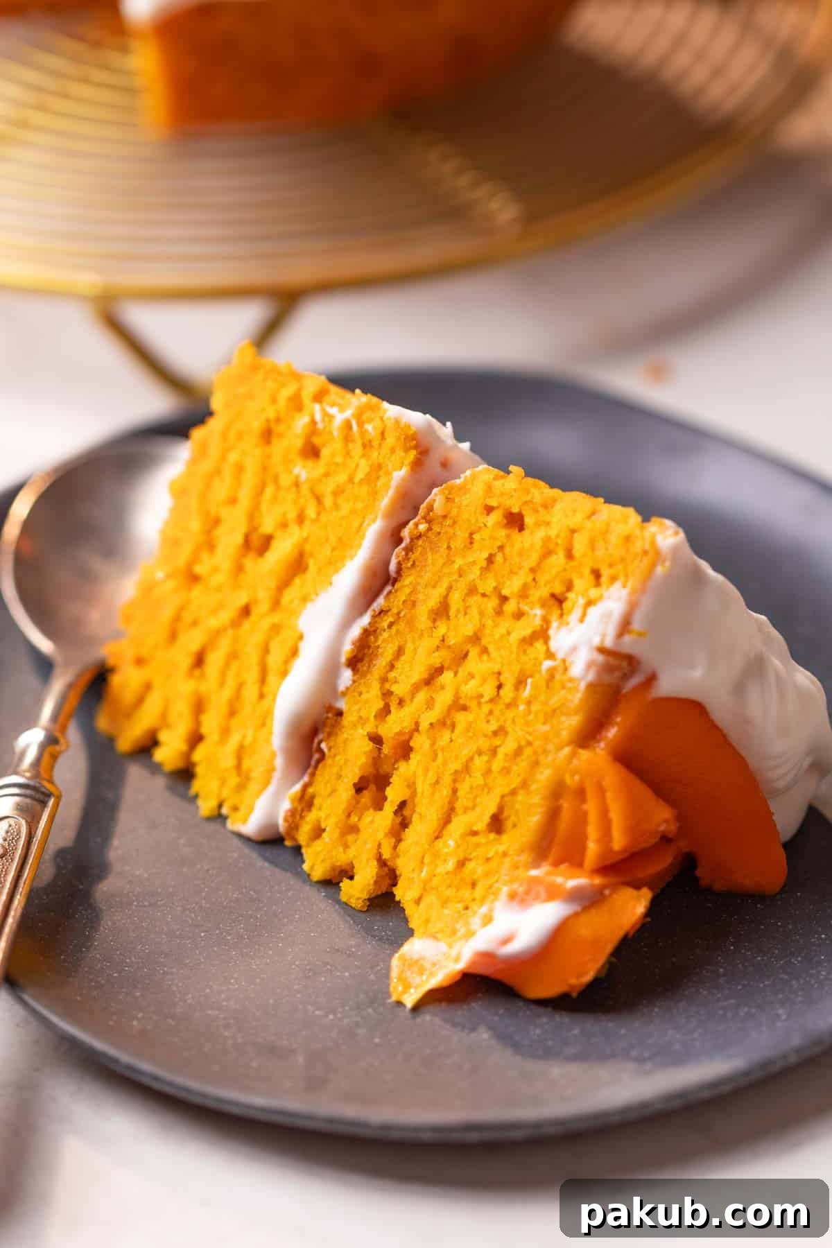 Sunshine Mango Delight 3 A slice of moist eggless mango cake on a white plate, showcasing its soft crumb and golden color.