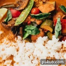 Close-up of Instant Pot Thai chicken curry served in a bowl with rice, Thai red chilies and lemon wedges