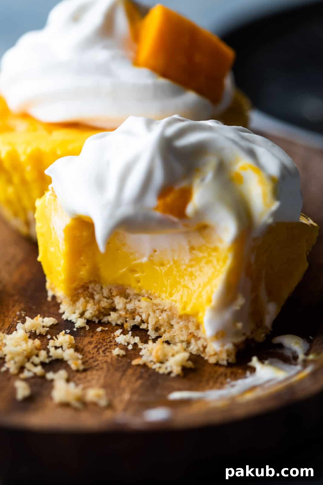 Closeup of a bite takes out of mini mango cheesecakes to show texture, highlighting the smooth mango filling and crunchy base