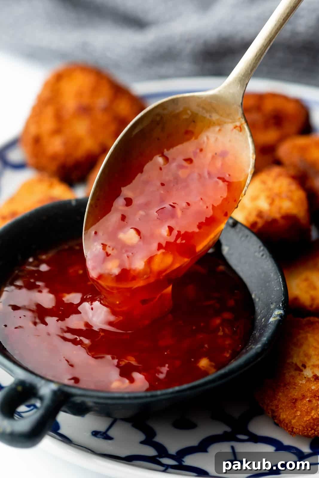 Closeup of Thai sweet chili sauce dripping off a spoon, highlighting its shiny, sweet, sticky texture