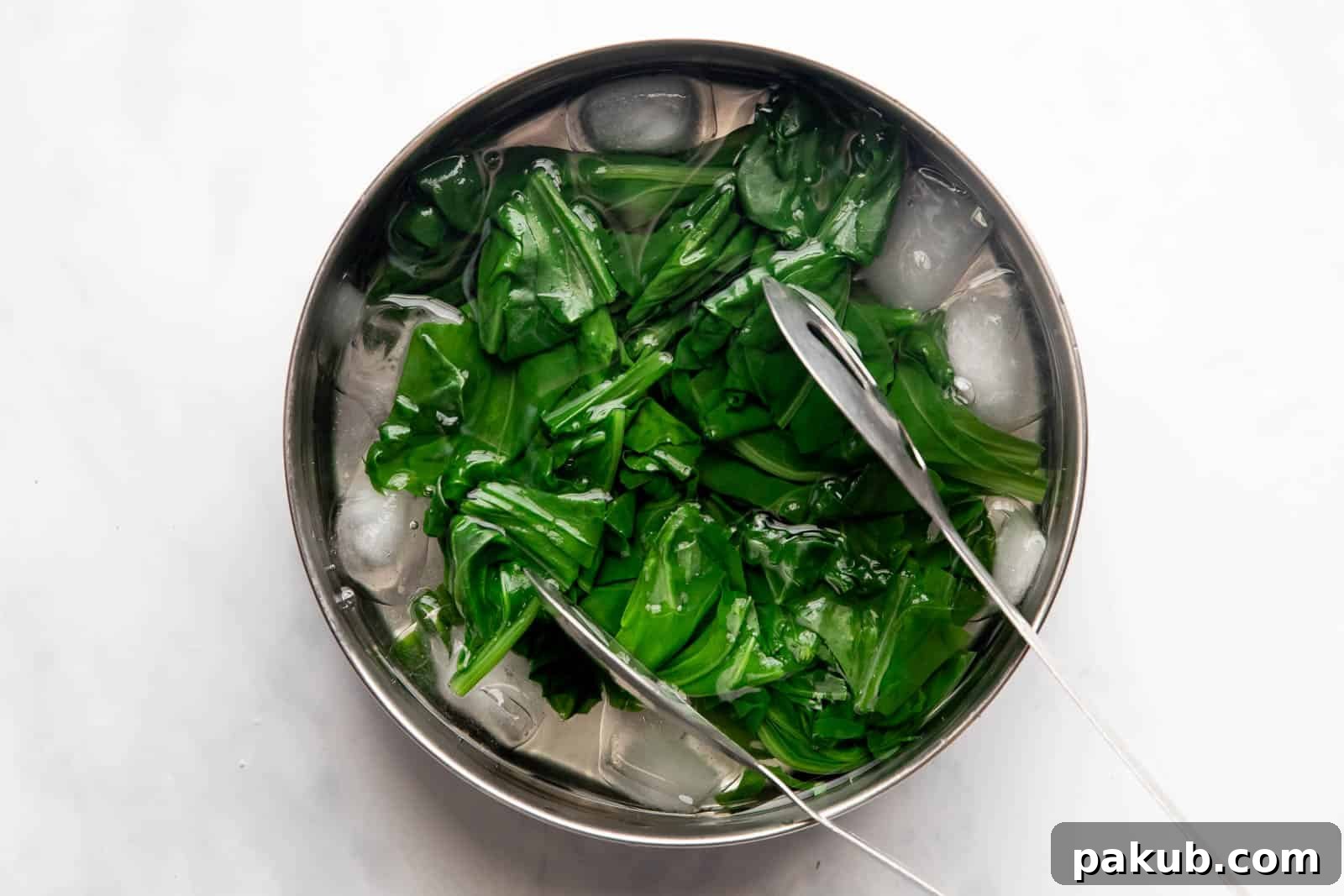 Spinach Magic Three Ways From Pan to Freezer 4 Blanched spinach being transferred from hot water into a bowl of ice-cold water to halt the cooking